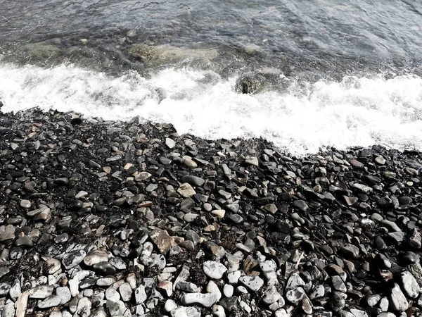波、スカコ、アナパ、クラスノダール準州、ロシアと海の岩のビーチ。上からの小石のビーチビューの海の泡。水の中に大きな丸みを帯びた小石や岩。水平写真黒海,コーカサス — ストック写真