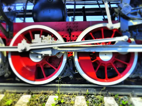 Roțile retro de epocă ale unei locomotive sau ale unui tren se apropie. Roți mari de metal greu roșu cu mecanisme de ghidare cu piston. Locomotiva secolelor XIX-XX cu un motor cu aburi. Fotografie luminoasă vie — Fotografie, imagine de stoc
