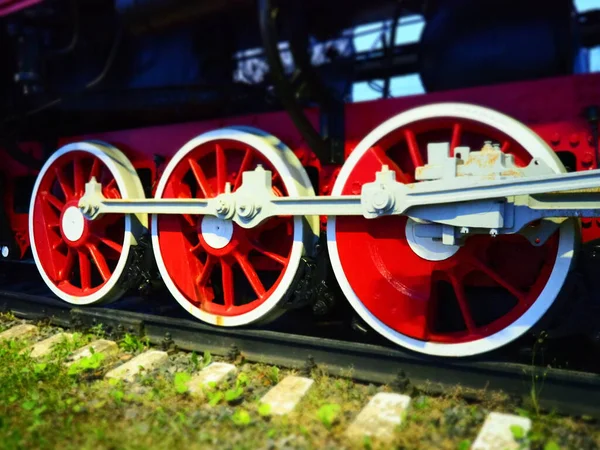 Retro vintage kola lokomotivy nebo vlaku zblízka. Červená velká těžká kovová kola s pístovým naváděcím mechanismem. Lokomotiva 19. až 20. století s parním strojem. Jasná živá fotografie — Stock fotografie