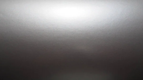 Silber - grauer Hintergrund mit metallischem Glanz, Licht von oben. Abstrakter Hintergrund mit Farbverlauf. Kopierraum. Struktur und Unebenheiten auf der Oberfläche des Papiers oder der Folie. Glanzfolie — Stockfoto