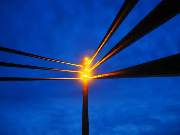 Proyectores en el puente. Torre de luz led portátil. Puente peatonal de San Ireneo sobre el río Sava, Sremska Mitrovica, Serbia. Cielo azul de noche con nubes. Pilares y vigas metálicas, perspectiva —  Fotos de Stock