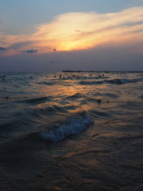 Denizin üzerinde gün batımı. Gün batımında güzel dalgalar. Turist Mekke, tatil köyü. Akşam gökyüzü. Işınlar sudan yansıyor..