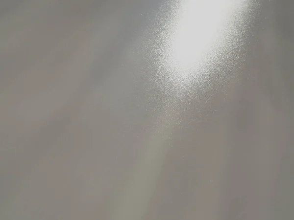 Raios de luz diagonais em um fundo cinza. Efeito de luz de fundo abstrato desfocado, vazamentos de luz. Iluminação da superfície lateral. Pequenas faíscas e brilho. Brilho, brilho ou brilho. Parte superior direita esquerda para baixo — Fotografia de Stock