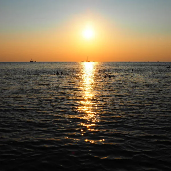 2021年8月23日，俄罗斯安纳帕，落日。日落时美丽的海浪。游客梅卡，度假胜地。夜晚的天空。光线从水中反射出来.船只和在海里游泳的人 — 图库照片