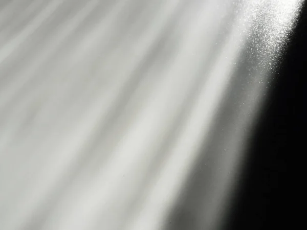 Diagonal rays of light on a gray background. Blurred abstract background light effect and leaks. Side surface illumination. Parallel, divergent and asymmetric lines, stripes of light at an angle