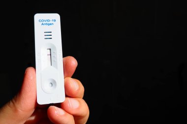 COVID-19 için test sonuçları negatif, enfeksiyon değil, hızlı test ekipmanları kullanılarak. Elinde koronavirüs testi, siyah arka plan. Uzayı kopyala Konsept Coronavirus Hastalığı Testi.