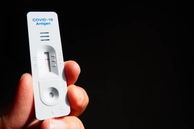 COVID-19 için test sonuçları negatif, enfeksiyon değil, hızlı test ekipmanları kullanılarak. Elinde koronavirüs testi, siyah arka plan. Uzayı kopyala Konsept Coronavirus Hastalığı Testi