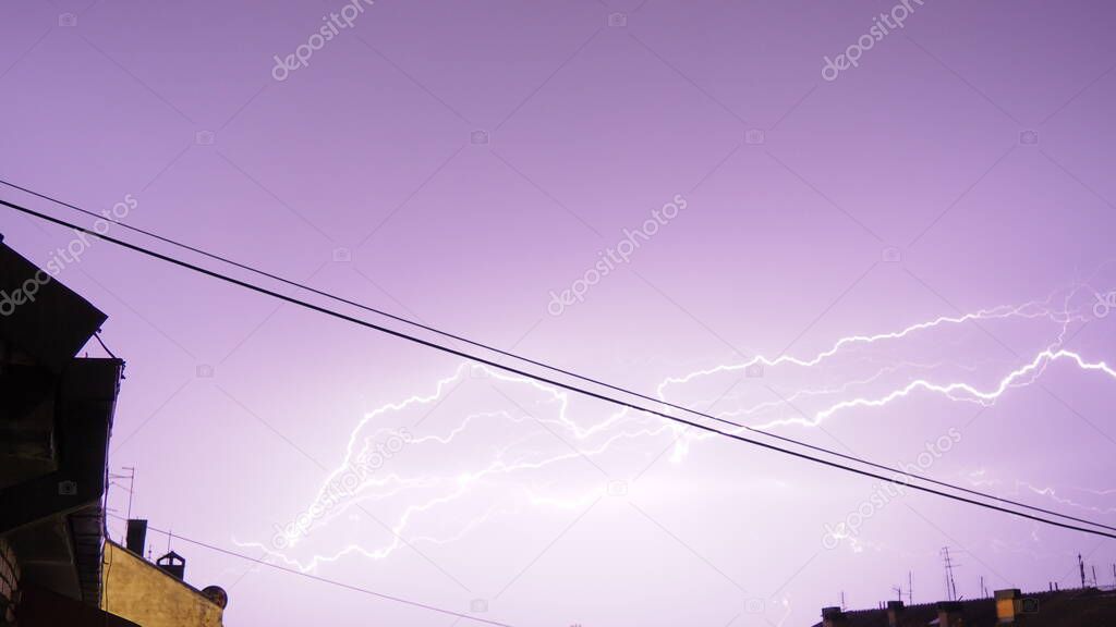 Lightning during a thunderstorm. Many lightning strikes over the roofs of houses in the city. Stormy terrible weather. Discharges of electricity in the atmosphere. Horizontal lightning flare. Serbia