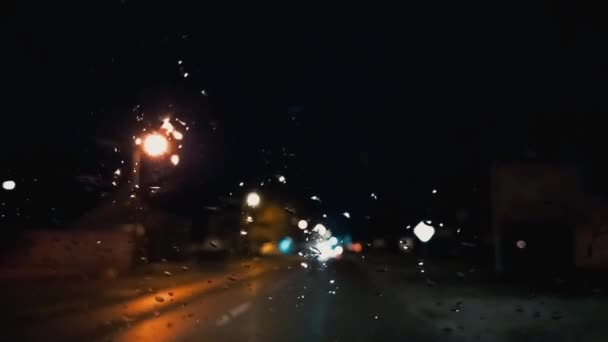 Driving at night. Raindrops on the windshield of the car. Asphalt road or track. Blurred and defocused effect. Focus on the droplets on the glass. Night lights, cars, road signs. Serbia, Srem