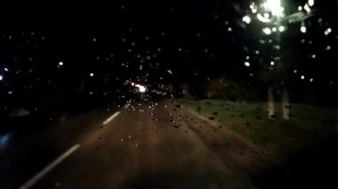 Geceleri trafik vardı. Arabanın ön camında yağmur damlaları var. Asfalt yolu ya da patika. Bulanık ve odaksız etki. Camdaki damlacıklara odaklan. Gece lambaları, arabalar, yol işaretleri. Yüksek hız. Sırbistan