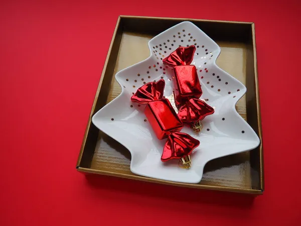 一个形状像圣诞树的盘子 上面有黄金饰品 中间有一颗星星 礼物包装 红色背景 糖果在红色的包装 背投广告和信件 礼物的准备 — 图库照片