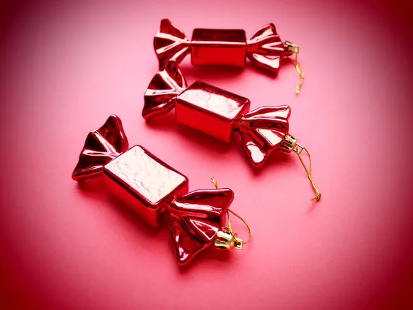 以糖果为形式的圣诞装饰 三只包装在粉色背景上的糖果 新年和圣诞节漂亮的装饰品 挂的线 粉色洋红色背景与肩章 — 图库照片