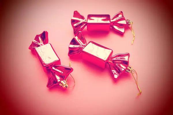 以糖果为形式的圣诞装饰 三只包装在粉色背景上的糖果 新年和圣诞节漂亮的装饰品 挂的线 粉红背景 带有小号 — 图库照片