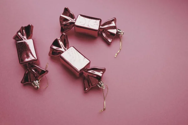 以糖果为形式的圣诞装饰 三只包装在和平粉色背景下的糖果 新年和圣诞节漂亮的装饰品 挂的线 粉色背景 复制空间 — 图库照片