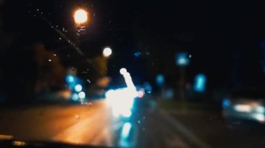 Geceleri trafik vardı. Arabanın ön camında yağmur damlaları var. Asfalt yolu ya da patika. Bulanık ve odaksız etki. Camdaki damlacıklara odaklan. Gece lambaları, arabalar, yol işaretleri. Yüksek hız. Sırbistan