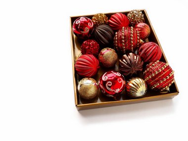 Beyaz arka planda bir kutuda Noel süsleri. Parlak ve çizgili güzel kırmızı ve altın toplar. Yılbaşı tatiline hazırlanıyorum. Güzel dekorasyonlar. Boşluğu kopyala