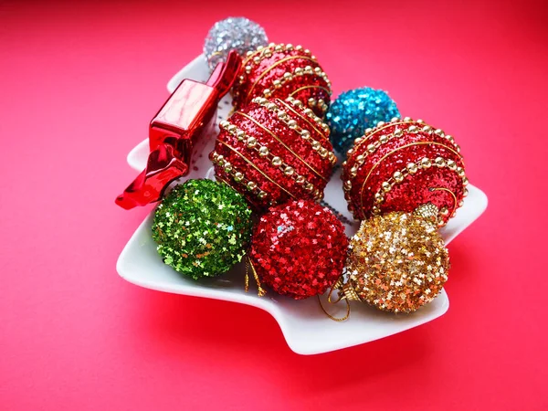 五彩缤纷的圣诞球和糖果在白色的盘子里 形状像一棵圣诞树 红色粉色背景 漂亮的条纹红 金圣诞装饰品 — 图库照片