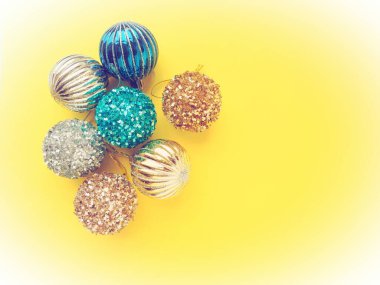 Sarı arka planda Noel süsleri. Parlak ve çizgili güzel mavi, gümüş ve altın toplar. Yılbaşı tatiline hazırlanıyorum. Güzel dekorasyonlar. Beyaz vignet