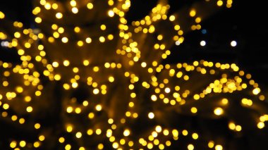 Noel gecesi Bokeh. Güzel yuvarlak bokeh röfleleri. Karanlıkta sarı ve altın rengi yanıp sönüyor. Yeni yıl için şenlikli bir geçmiş. Mutlu Noeller. Bulanık defocus. Şehir sokaklarının dekorasyonu