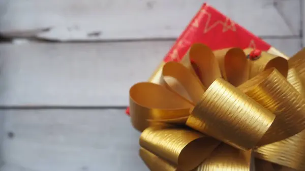 Czerwone pudełko z dużym złotym łukiem na drewnianym tle malowane białą farbą. Prezent na Boże Narodzenie, Nowy Rok, Urodziny, Dzień matki, Ślub, Walentynki. Piękna dekoracja świąteczna — Zdjęcie stockowe