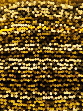 Bokeh röfleleri. Karanlıkta sarı ve altın rengi yanıp sönüyor. Şenlik arka planı. Bulanık defocus. Şehir sokaklarının dekorasyonu. Bir sürü sarı top. Birçok sarı, beyaz ve turuncu daireler