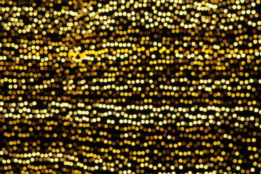Bokeh röfleleri. Karanlıkta sarı ve altın rengi yanıp sönüyor. Şenlik arka planı. Bulanık defocus. Şehir sokaklarının dekorasyonu. Bir sürü sarı top. Birçok sarı, beyaz ve turuncu daireler