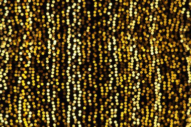 Bokeh röfleleri. Karanlıkta sarı ve altın rengi yanıp sönüyor. Şenlik arka planı. Bulanık defocus. Şehir sokaklarının dekorasyonu. Bir sürü sarı top. Birçok sarı, beyaz ve turuncu daireler