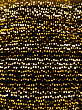 Gece gökyüzünün arka planında asılı çelenkler. Şehir sokaklarının şenlikli dekorasyonu. Sarı, beyaz ve altın renkli çelenkler ve ampuller. Yeni yıl için güzel bir geçmiş, Noel tatili