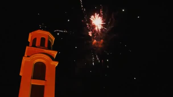 Fireworks for Christmas. Beautiful flashes and flashes of fire and fireworks against the background of the night sky and a Christian church with a cross. Multiple explosions of pyrotechnics