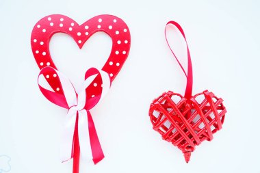 Valentine's day concept. Two red hearts. Wooden heart with white dots and a ribbon bow on a stick. Wicker heart with a loop. White background. Flat lay.