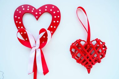 Valentine's day concept. Two red hearts. Wooden heart with white dots and a ribbon bow on a stick. Wicker heart with a loop. White background. Flat lay.