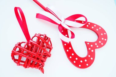 Valentine's day concept. Two red hearts. Wooden heart with white dots and a ribbon bow on a stick. Wicker heart with a loop. White background. Flat lay.