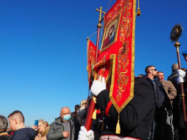 Sremska Mitrovica, Sırbistan, 19 Ocak 2022. Hristiyan bayramı temennisi. Nehirde yıkanan insanlar. Kilise gereçleri, ayinler, bayraklar ve çalışanlar merdivenlerden aşağı iniyor.