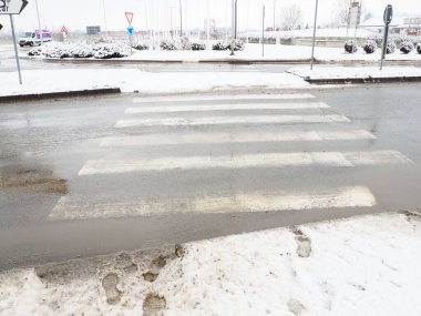 Yaya geçidinde kar, buz, çamur ve kış çamuru. Hava sıcaklığı yaklaşık 0 derece. Zorlu sürüş koşulları. Arabanın fren mesafesi. Trafik kanunları. Altyapı ve karayolu hizmetleri.