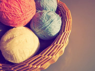 Yün ve akrilik iplikler. Hobi olarak örgü örüyorum. Aksesuarlar, iplik yumakları ve hasır sepetin içinde beyaz, pembe ve mavi renkler. Boşluğu kopyala.