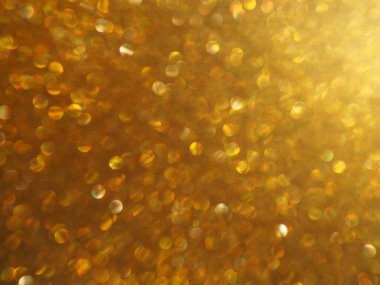 Altın parıltılarının Bokeh ışığı. Altın parıltı dokusu arka planı. Pullu ve pırıltılı, ışıltılı ambalaj kağıdı. Şenlikli altın bokeh ve parıltı. Güzel makro arkaplan.