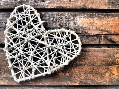 Kırsal ışık çubuklarından ya da ipliklerden örülmüş bir kalp. El yapımı hassastır. Sevgililer Günü. Kartpostal Ahşap doku arka planı. Aşk konsepti.