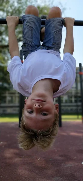 Boy Hangs Upside Sports Ground Exercises Sports Equipment Caucasian Child — Stock Photo, Image