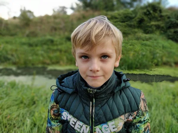 Sremska Mitrovica 2021年10月18日閲覧 8歳の金髪の少年が沼のそばを歩いている 暖かい緑色の服 仰向けに — ストック写真