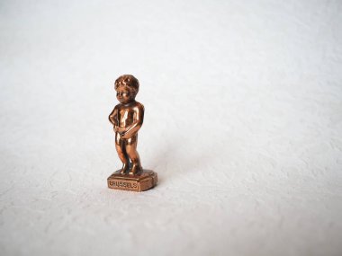 Beyaz arka planda Manneken Pi heykeli. Brüksel sembolü. Havuza işeyen çıplak bir çocuğun minyatür bronz heykelciği. Metal hatıra. Bebek işiyor..