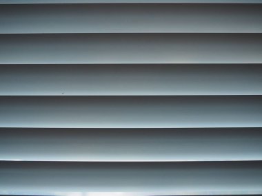 Pencere perdeleri. Yatay çizgili beyaz panjurlar. Oturma odası penceresi, otel odası ya da ofis. Sabah güneşi perdelerin arasından doğuyor. Moda ve pratik iç tasarım