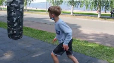 Petrozavodsk, Rusya, 11 Temmuz 2021. 9 yıllık koruyucu bir maske takmış boks çantasıyla gezen bir çocuk. Spor ve açık hava egzersizleri. Tekmeler ve yumruklar. Dövüş sanatı.