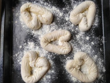 Hamurdan yapılmış, un serpiştirilmiş, siyah bir çarşafın üzerinde duran kalpler şeklinde simit.