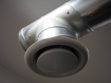 Umumi tuvalette çıkarıcı kaput. Gri hava çıkarıcılı yuvarlak metal boru. Mühendislik havalandırma sistemleri. Odanın tavanının altındaki galvanize borular. Plastik yuvarlak uç.
