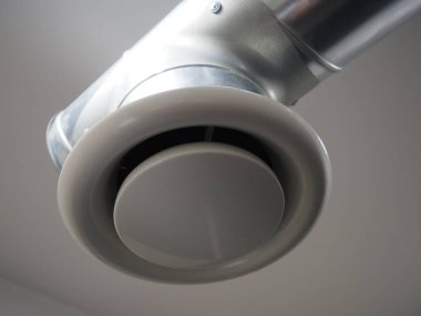 Umumi tuvalette çıkarıcı kaput. Gri hava çıkarıcılı yuvarlak metal boru. Mühendislik havalandırma sistemleri. Odanın tavanının altındaki galvanize borular. Plastik yuvarlak uç.