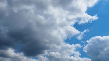 Mavi gökyüzüne karşı hızlı hareket eden bulutlar. Bulutlu kümülüs bulutları rüzgarda gittikçe daha alçaktan ve daha hızlı hareket eder. Meteoroloji ve hava tahmini. Ekolojik sorunlar. İklim değişikliği. Fırtına rüzgarı zaman aşımı.