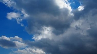 Mavi gökyüzüne karşı hızlı hareket eden bulutlar. Bulutlu kümülüs bulutları rüzgarda gittikçe daha alçaktan ve daha hızlı hareket eder. Meteoroloji ve hava tahmini. Ekolojik sorunlar. İklim değişikliği. Fırtına rüzgarı zaman aşımı.