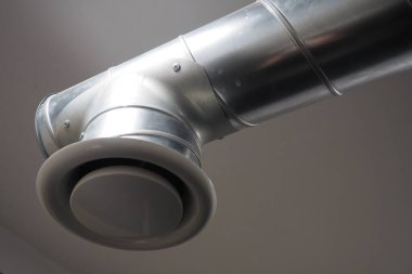 Umumi tuvalette çıkarıcı kaput. Gri hava çıkarıcılı yuvarlak metal boru. Mühendislik havalandırma sistemleri. Odanın tavanının altındaki galvanize borular. Plastik yuvarlak uç.