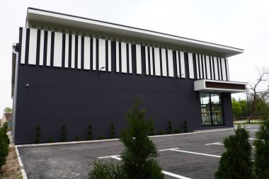 Modern bina. Thuja biçimli bir taç ile. Modern peyzaj tasarımı. Bahçenin, çimlerin, evin güzel dekorasyonu. Çizgili dekorlu gri duvar, QR kodunun taklit edilmesi, araba parkı.