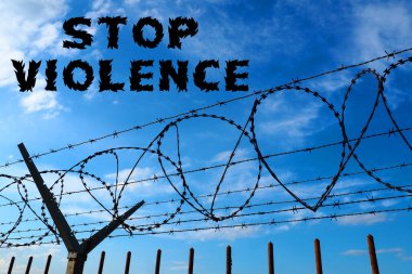 Barbed wire against the blue sky. The inscription in black stop violence. No to violence. The concept of freedom, human rights, imprisonment, restrictions, war, struggle and protest.